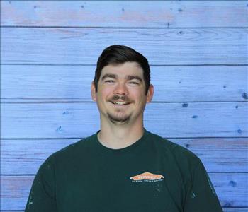Male employee smiling in front of background of wooden wall