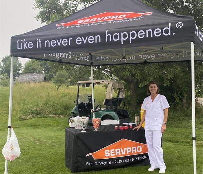 female in scrubs standing in front of table under golf tent